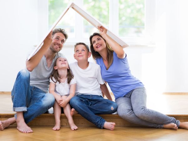 Symbolbild einer Familie mit einem Pappdach über dem Kopf
